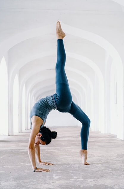 Yoga student performing a graceful backbend in a white arched corridor