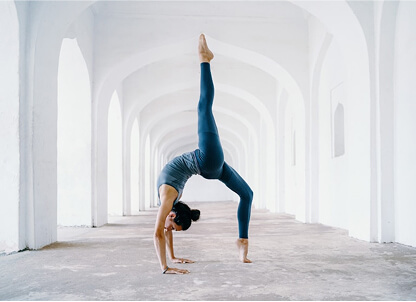Yoga student in a deep backbend inside a white arched hallway