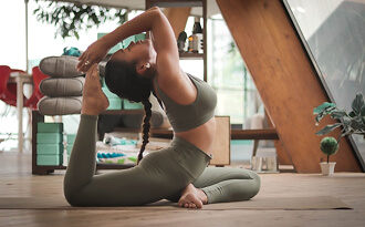 Student in an advanced seated backbend inside a bright yoga studio
